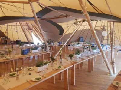 Long Rustic Tables Joined Together In Tipi For Festival Wedding