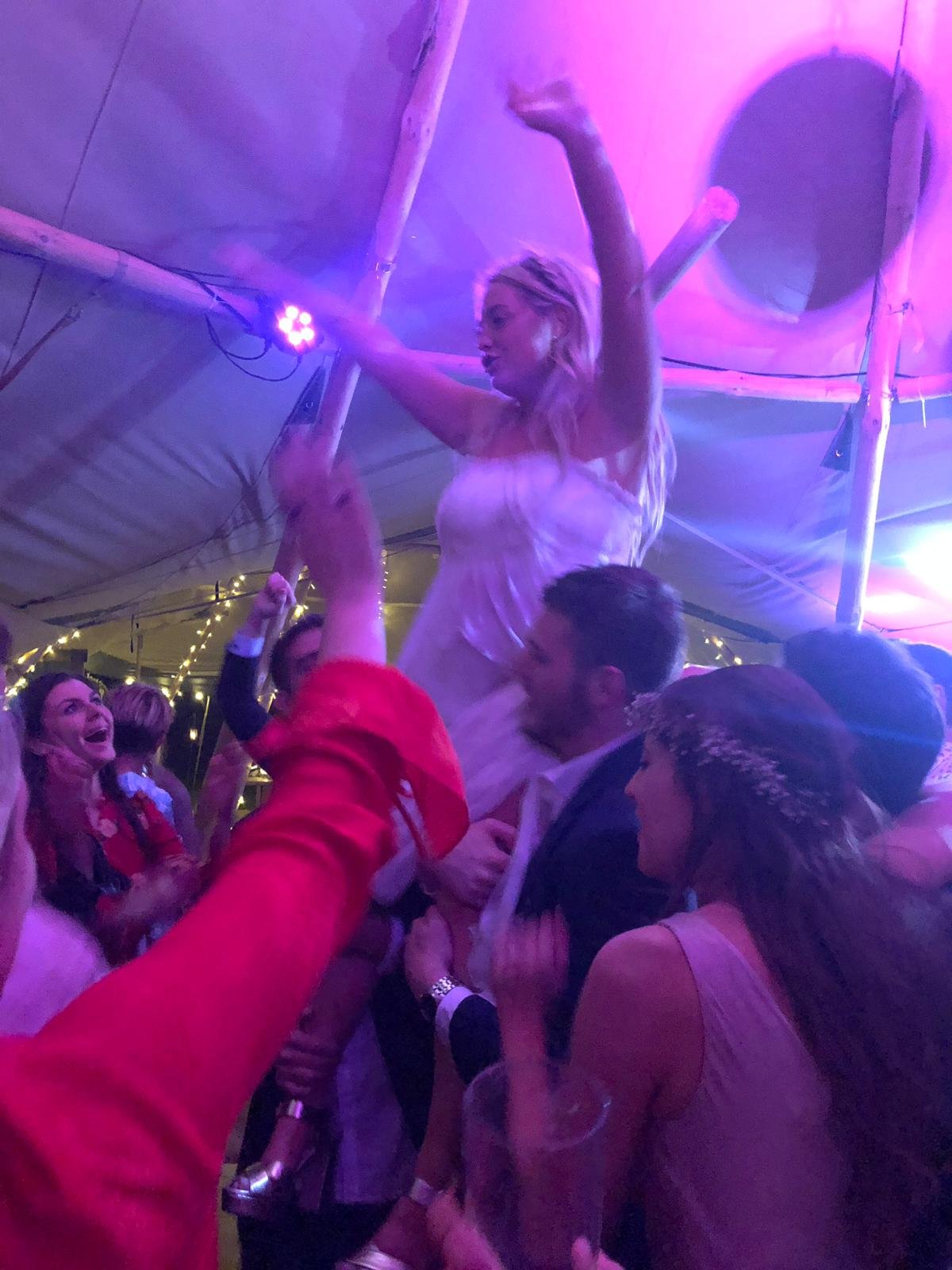 Bride partying at her tipi wedding. Coloured uplights add to effect
